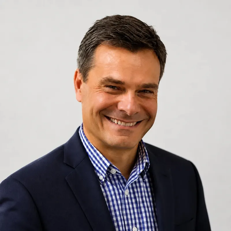 Harald Weinbrecht, smiling, in a navy jacket and blue gingham shirt